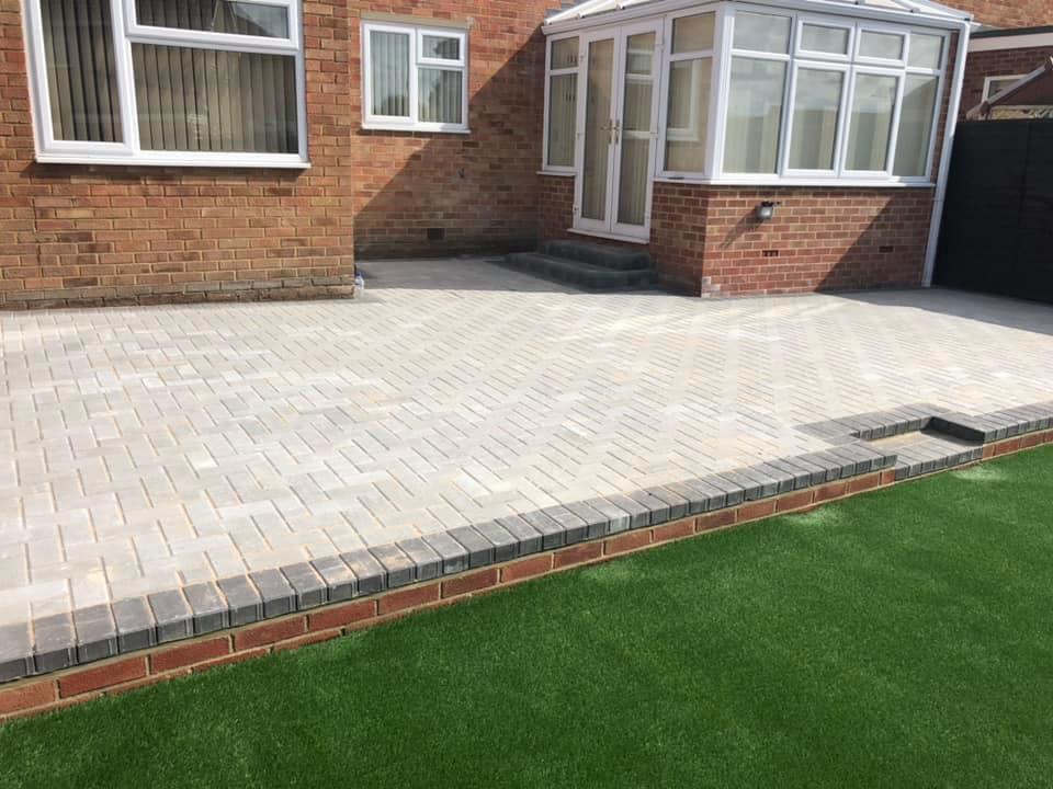 Front garden and driveway with light block paving and brick edging