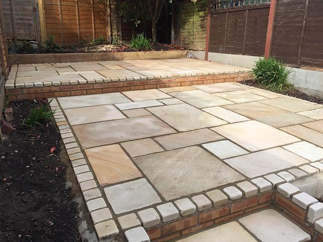 Finished raised patio with paving slabs and brick edging